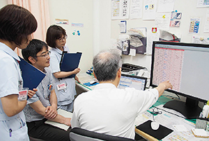ベッドコントロールシステムのデータを病棟回診やカンファレンスなどに活用。宮岡院長を中心にカンファレンスを行うスタッフ。